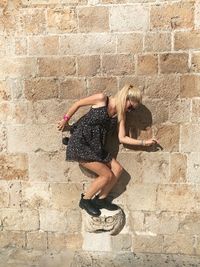Full length of young woman balancing against wall
