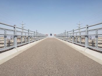 Vanishing point view of person jumping on footbridge