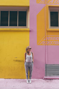 Portrait of young woman standing against window