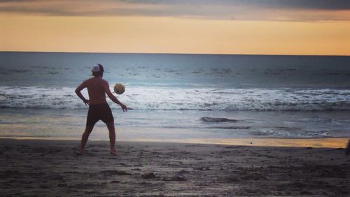 Full length of shirtless man walking on beach