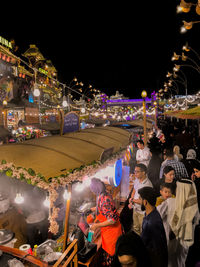 Crowd at illuminated market against sky in city at night