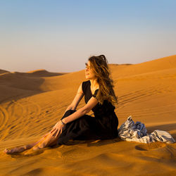 Beautiful woman sitting on sand in desert