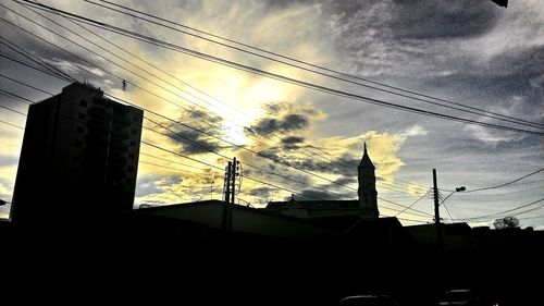 Low angle view of electricity pylon against cloudy sky