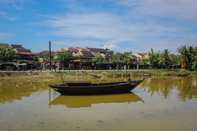 Boats in canal by building against sky