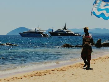 Rear view of woman standing on beach against clear sky