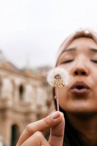 Close-up of woman blowing dandelion flower