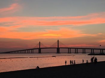 Silhouette of suspension bridge over sea