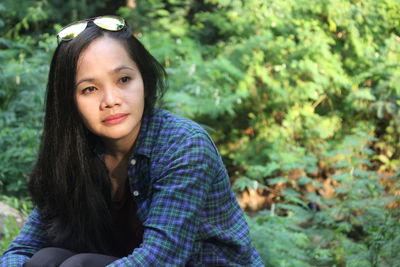 Portrait of beautiful young woman against trees