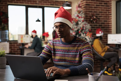 Portrait of young man using laptop while sitting on table