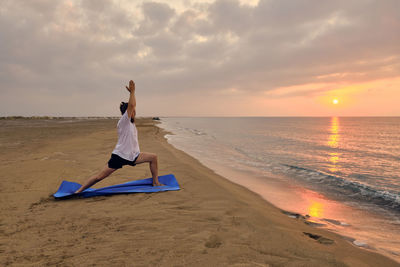 Man stands on blue exercise man doing virabhadrasana one pose. man practices warrior one asana