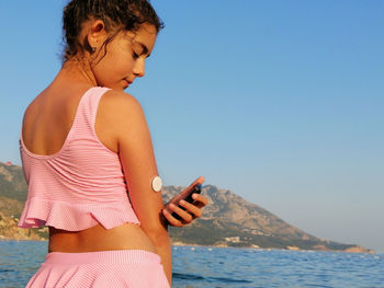 Life with diabetes. girl checks glucose level with cgm device before enters the sea.  