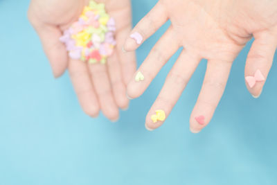 Cropped image of hands holding fondant over blue background