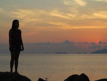 Rear view of man standing at beach during sunset