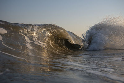 Close-up of waves splashing on shore against clear sky