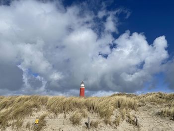 Lighthouse on street amidst buildings against sky