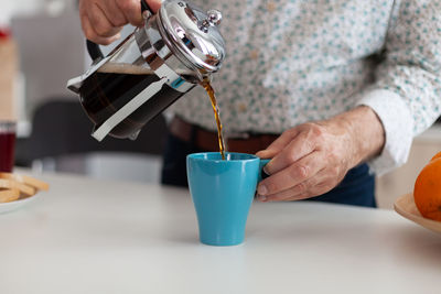 Midsection of person pouring coffee in cup