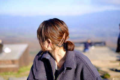 Woman looking away while sitting against sky