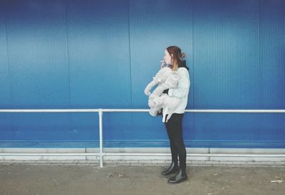 Young woman standing against blue wall