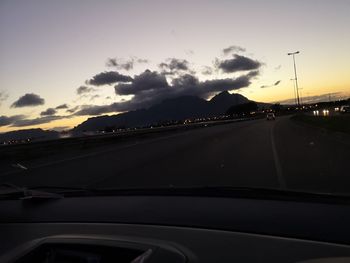 Cars on road against sky seen through car windshield