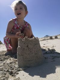 Full length of girl making sandcastle while crouching at beach