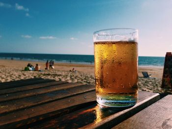 Close-up of drink in glass on wooden table at beach