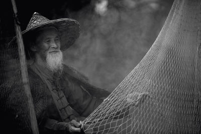 Man in hat looking at fishing net outdoors