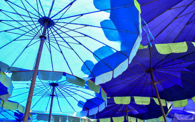 Low angle view of umbrellas hanging against blue sky