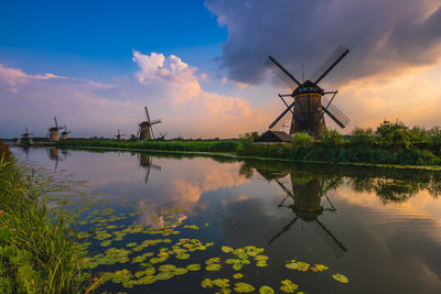 Traditional windmill against sky at sunset