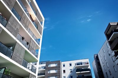 Low angle view of modern buildings against blue sky