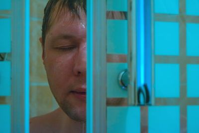 Close-up of mid adult man bathing seen through doorway