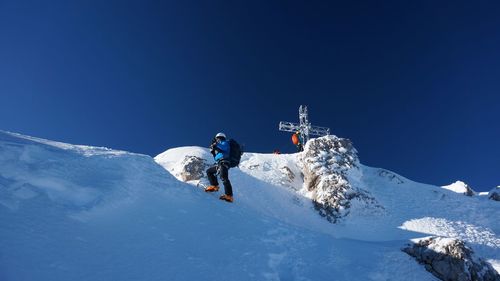 Low angle view of man on snowcapped mountain against sky