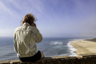 Rear view of woman looking at sea shore against sky