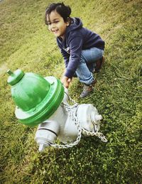 High angle view of playful child by fire hydrant on grassy field