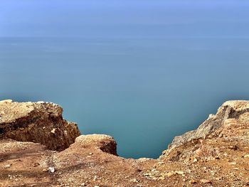 Rock formations by sea against blue sky