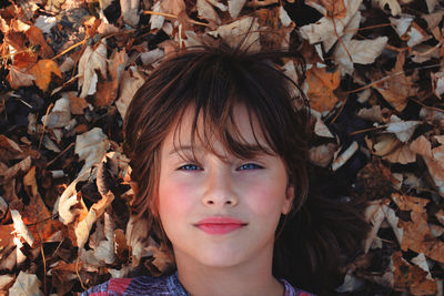 Portrait of girl with dry leaves during autumn
