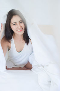 Portrait of smiling beautiful woman lying on bed at home