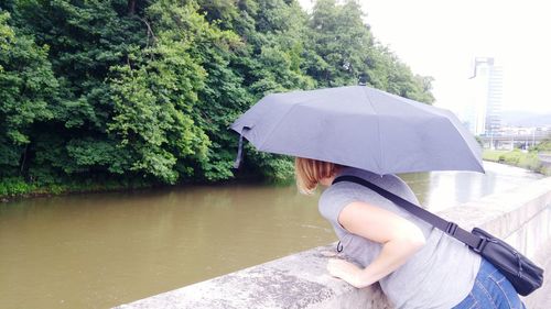 Woman with umbrella standing against canal in city