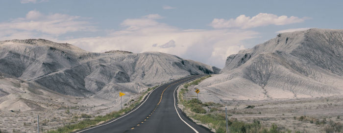 Empty road amidst mountains against sky