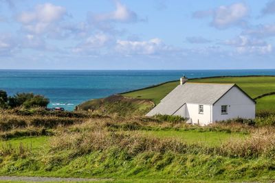 House on field by sea against sky