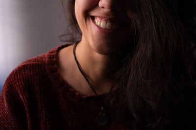 Midsection of smiling young woman sitting indoors