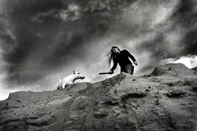 Low angle view of woman against cloudy sky