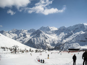 People on snowcapped mountains against sky