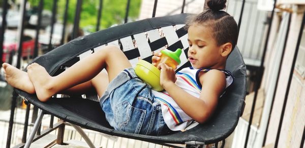 Cute boy with food and drink sitting on chair