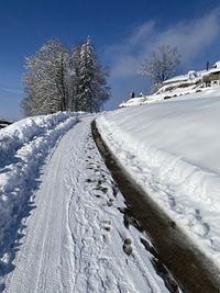 Tire tracks on snow covered field against sky