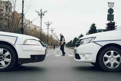 Side view of man crossing road against sky