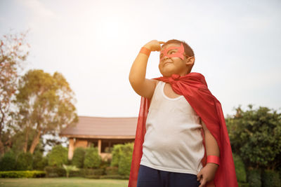 Boy with cape and eye patch playing in park