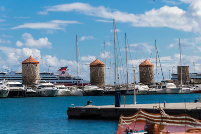 Sailboats moored in harbor against sky