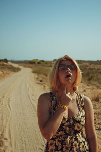 Young woman with arms raised standing against clear sky