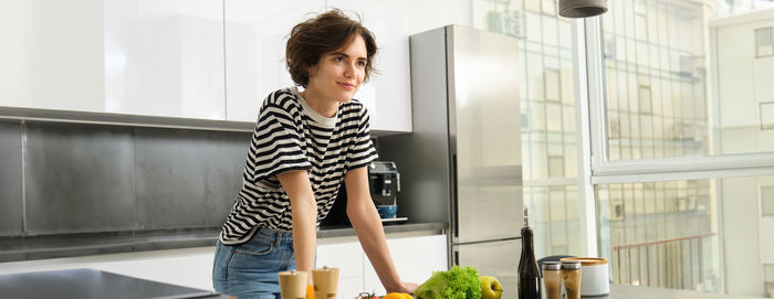 Side view of young woman standing in kitchen