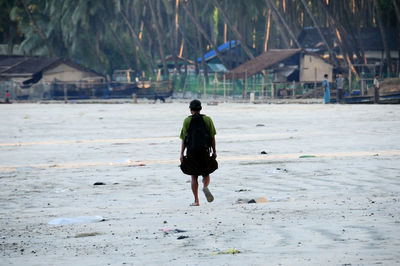 Rear view of man walking on beach